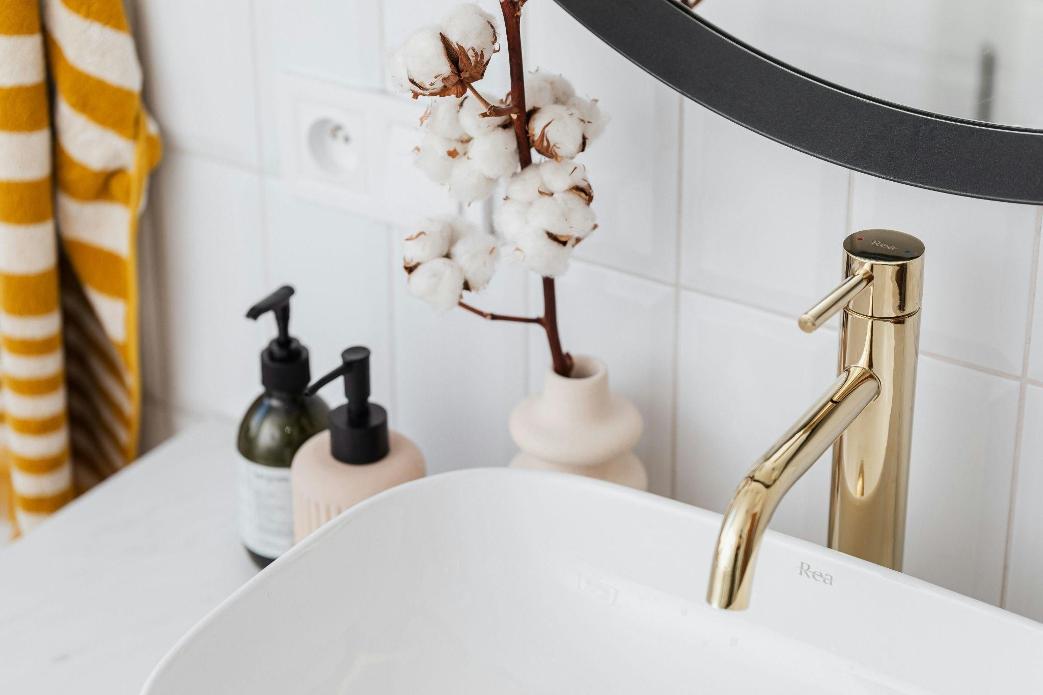 Close-up of gold metal bathroom sink fixture in a clean modern bathroom