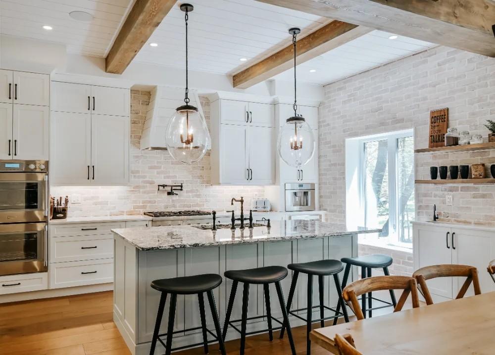 A timeless kitchen with hardwood floors, white cabinets, and beige brick backsplash